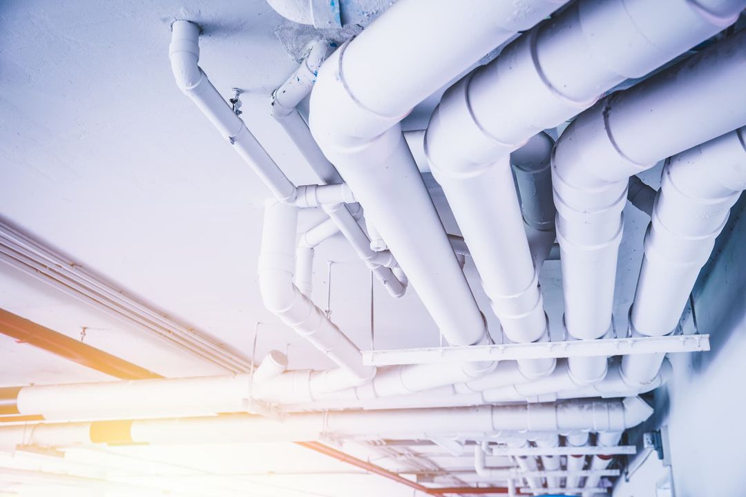 View of a complex network of white industrial pipes installed along a ceiling, demonstrating a well-organized piping system