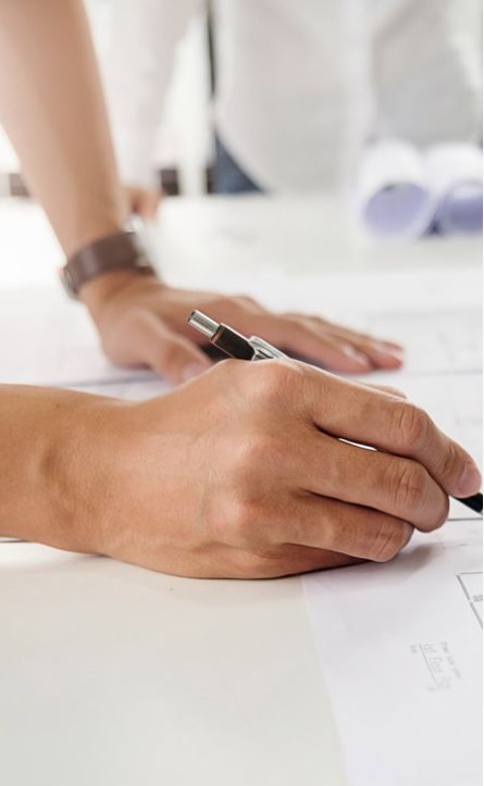 Close-up of an engineer's hand drawing a detailed HVAC system blueprint on a desk, focusing on precision and design accuracy.