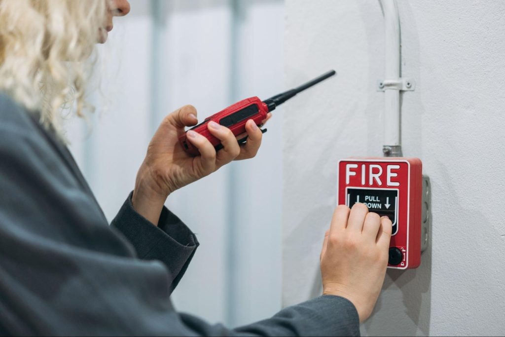Worker using walkie-talkie while testing fire alarm system