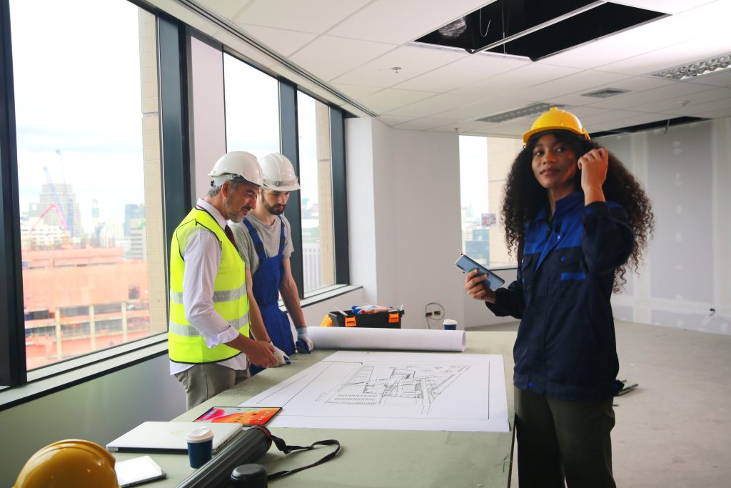 Engineers and architects reviewing blueprints inside a commercial building under renovation in Alberta, discussing project schedules and compliance.
